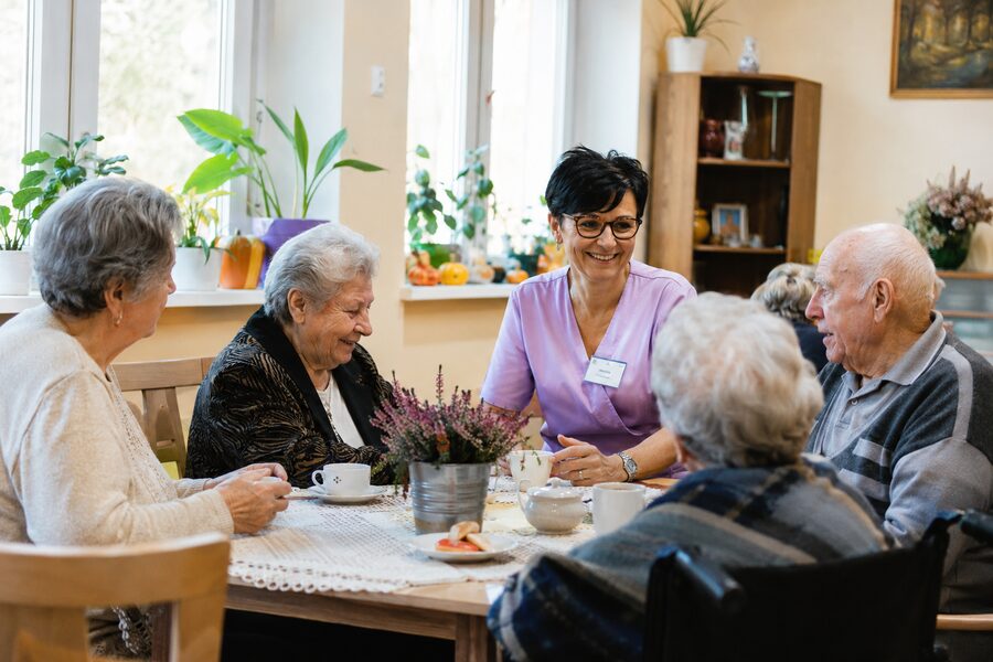Seniorzy z opiekunką przy stole w dziennym domu opieki